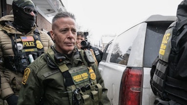 U.S. Border Patrol commander Gregory Bovino walks to his car as masked federal agents surround him.