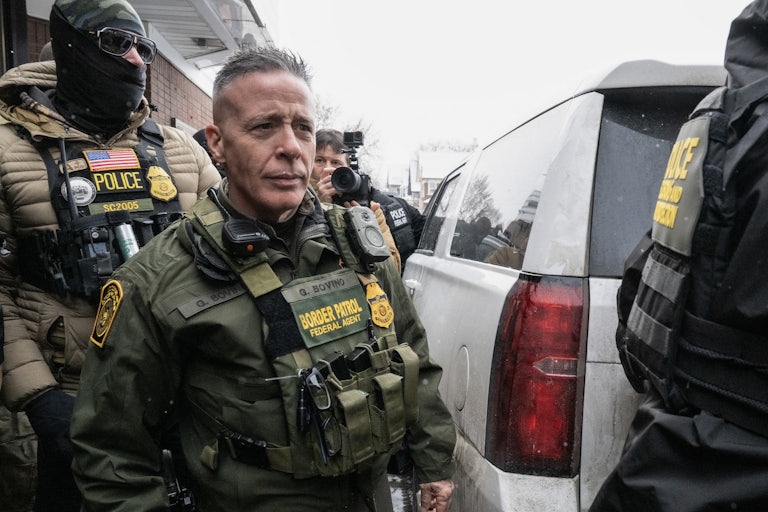 U.S. Border Patrol commander Gregory Bovino walks to his car as masked federal agents surround him.
