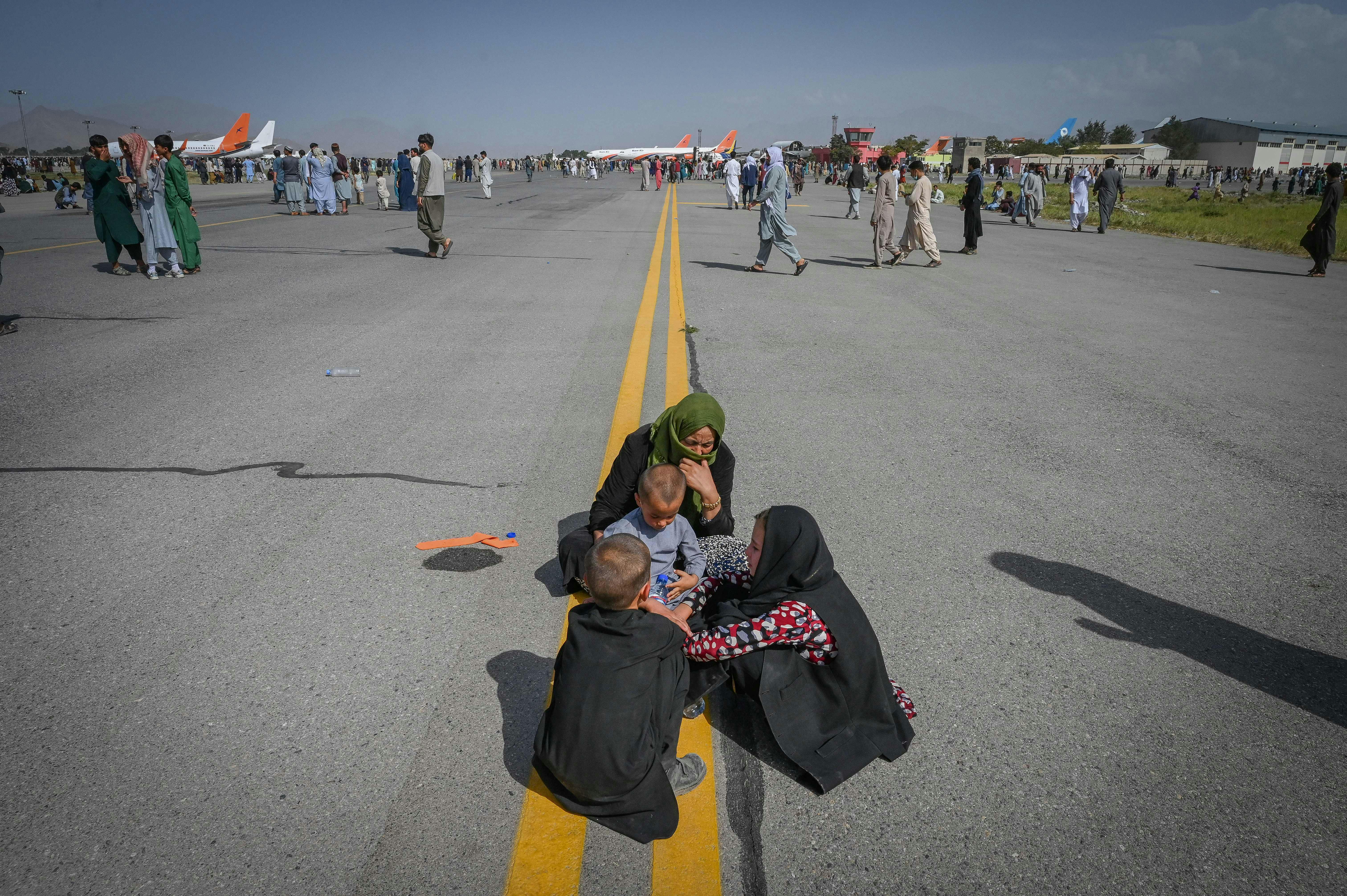 An Afghan woman and three children huddle on the tarmac of the airport in Kabul, Afghanistan.