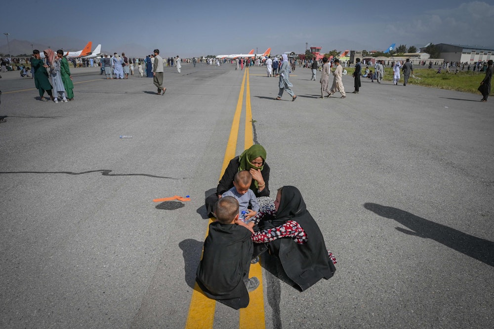 An Afghan woman and three children huddle on the tarmac of the airport in Kabul, Afghanistan.