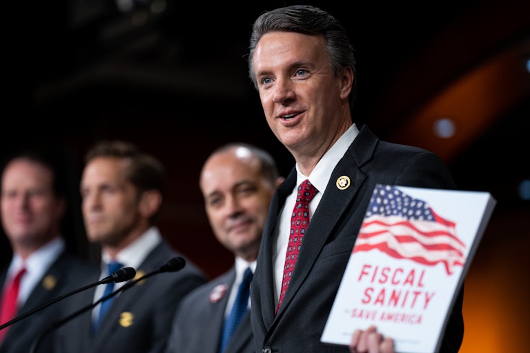 Representative Ben Cline holds up a packet labeled “Fiscal Sanity” while speaking at a microphone
