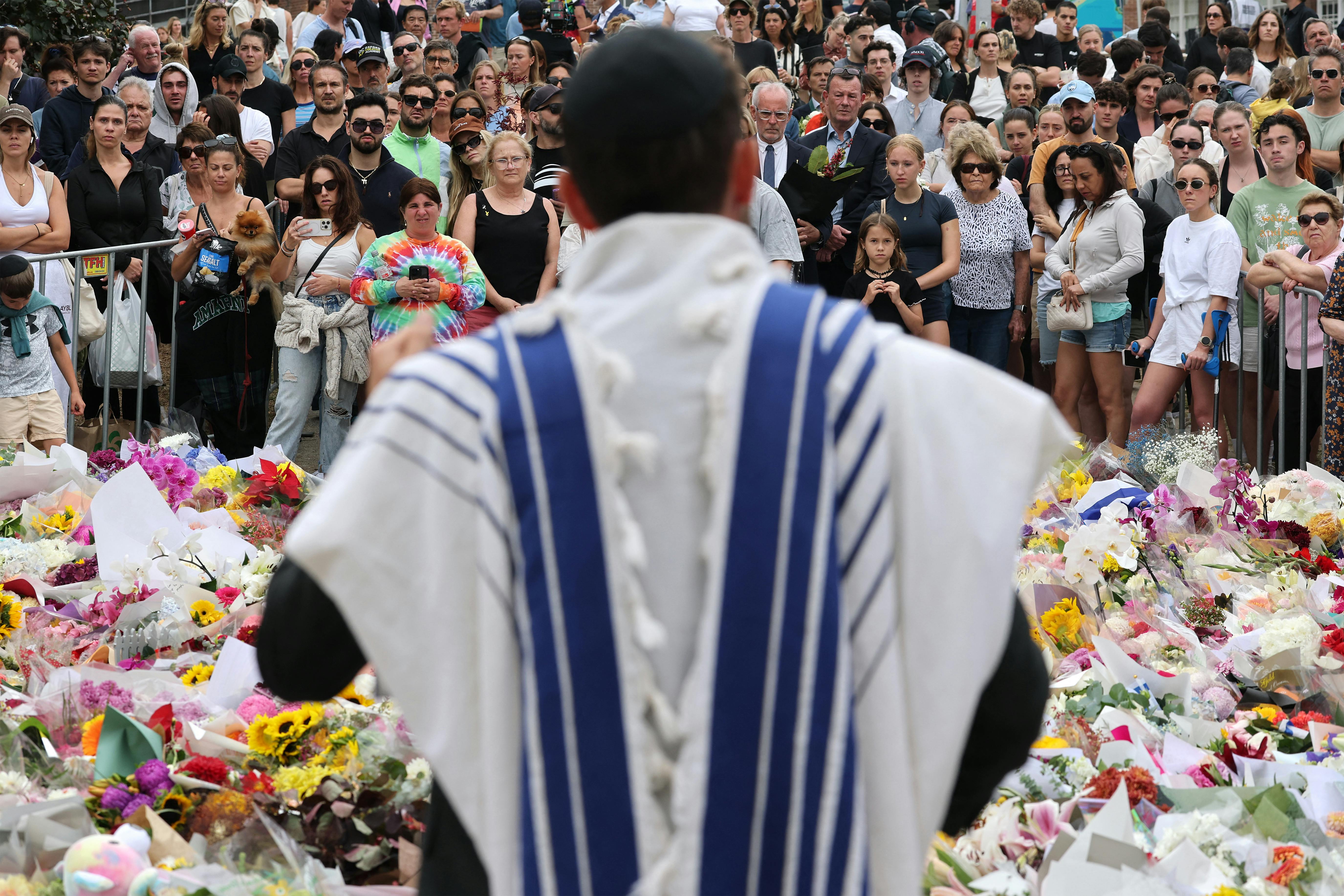 A rabbi speaks with mourners at a tribute outside Bondi Pavilion in Sydney