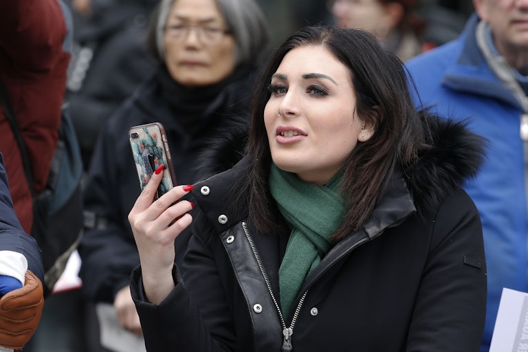 Laura Loomer holds her phone in front of her face and speaks