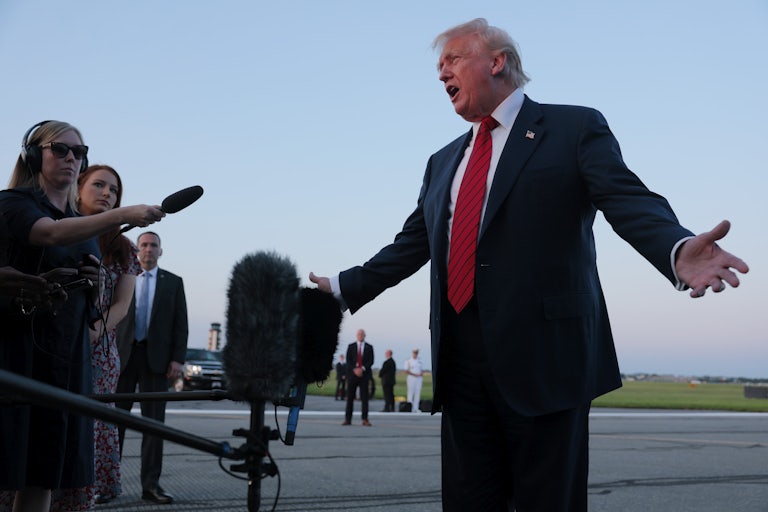 Donald Trump holds his arms out to the side while speaking to reporters on an airport tarmac