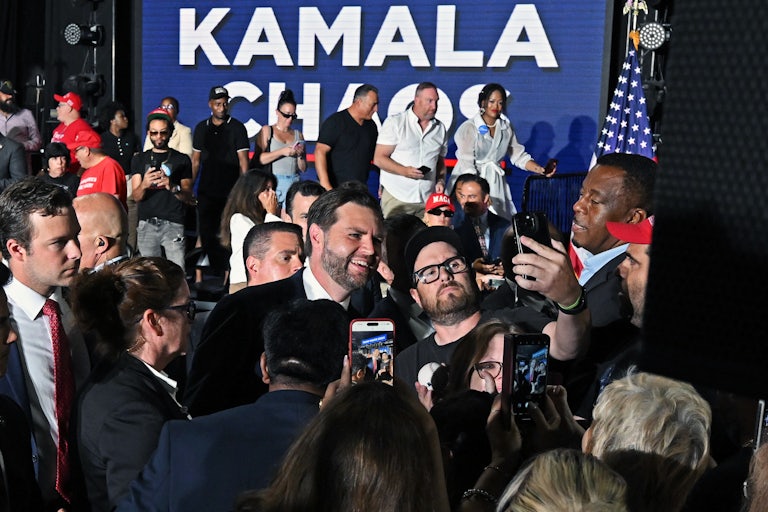 J.D. Vance takes photos with supporters in front of a sign that says “Kamala”