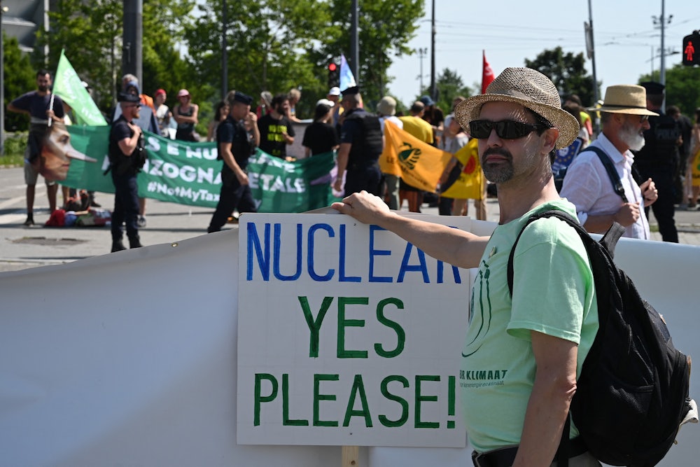 A pro-nuclear demonstrator holds a sign reading "NUCLEAR YES PLEASE!"