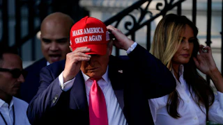 Donald Trump adjusts his Make America Great Again cap while Melania stands in the background.