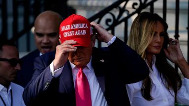 Donald Trump adjusts his Make America Great Again cap while Melania stands in the background.