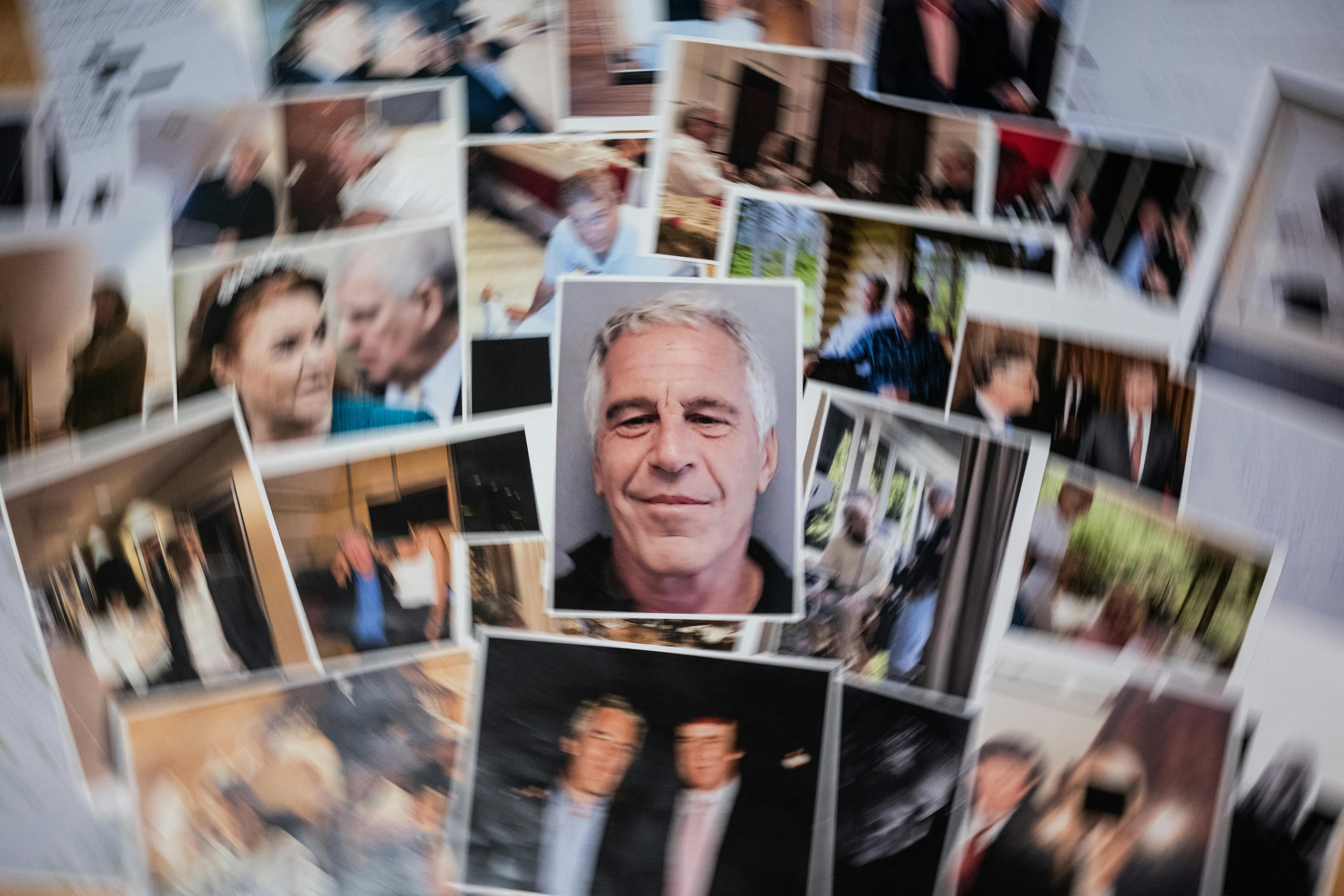 Unredacted photos of Jeffrey Epstein released by the Department of Justice spread on a table.