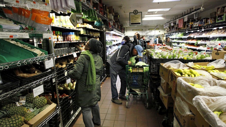 People stand in aisles stocked with food and beverages.