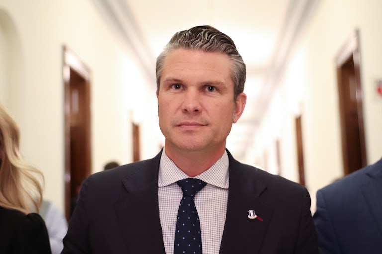 Pete Hegseth smiles while walking through the Capitol