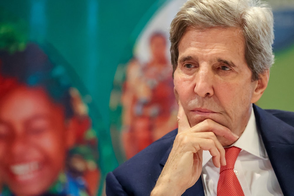 John Kerry sits with his head on his chin, looking contemplative.