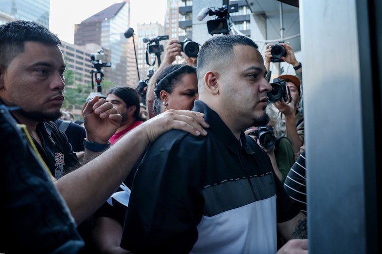 Kilmar Abrego Garcia walks into ICE custody as someone puts a hand on his shoulder.
