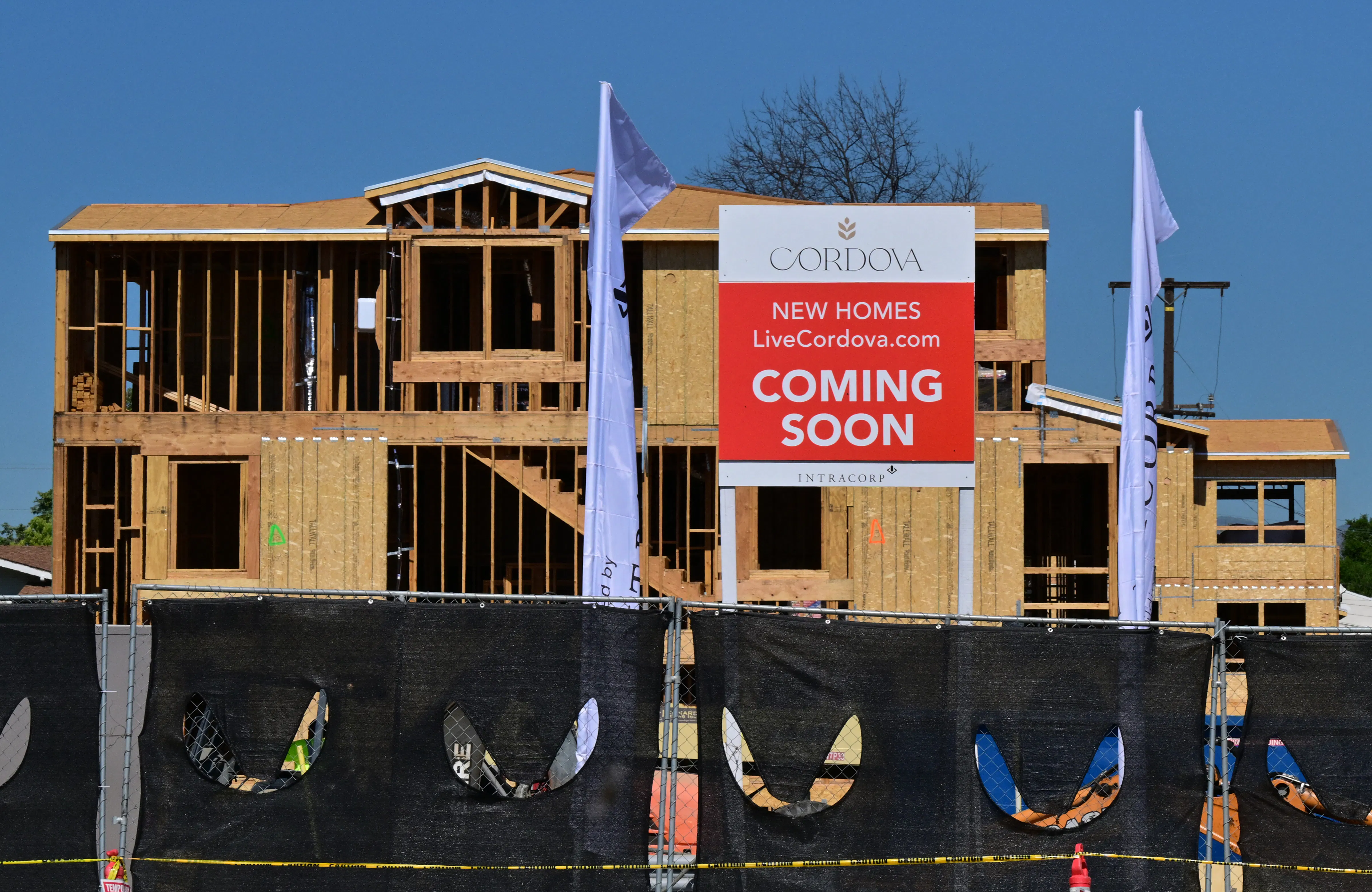 Plywood and wood framing are visible on a home still under construction, with a "Cordova New Homes Coming Soon" sign visible in front of the house frame. 