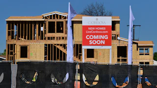 Plywood and wood framing are visible on a home still under construction, with a "Cordova New Homes Coming Soon" sign visible in front of the house frame.