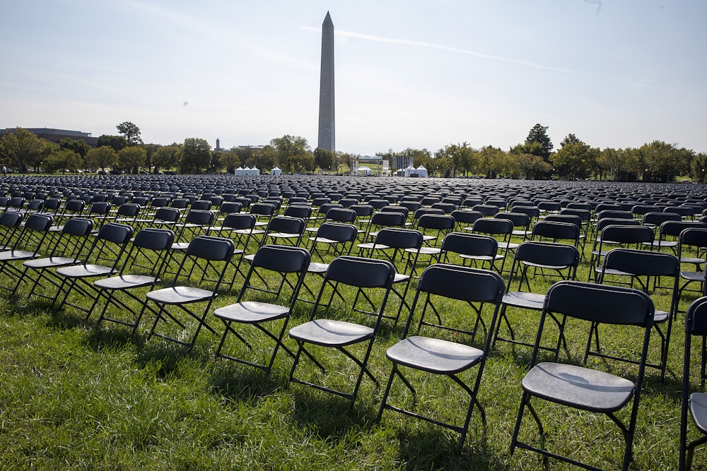 Rows and rows of empty chairs stand on grass, with the Washington Monument in the background.