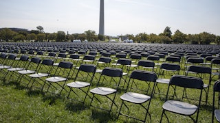 Rows and rows of empty chairs stand on grass, with the Washington Monument in the background.