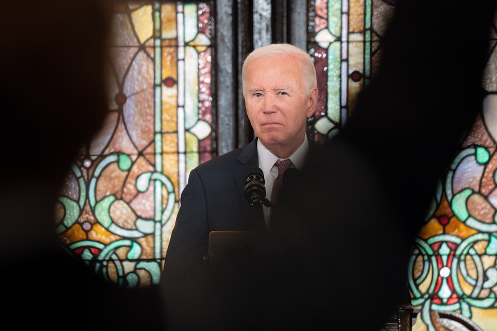 Joe Biden speaks at a church while a shadow obscures him slightly.