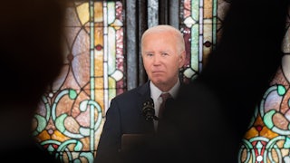 Joe Biden speaks at a church while a shadow obscures him slightly.