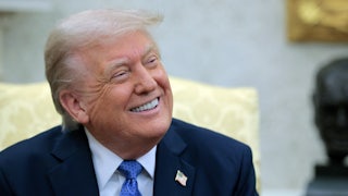 Donald Trump smiles while looking to his left.