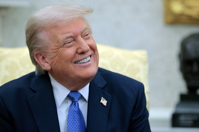 Donald Trump smiles while looking to his left.