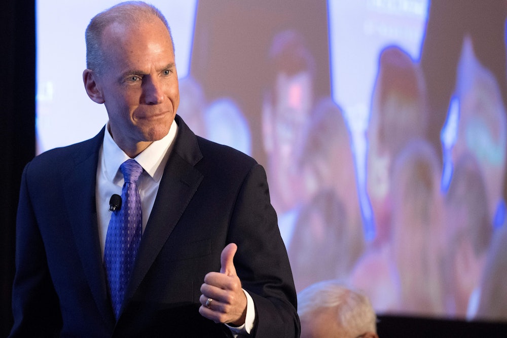 Former Boeing CEO Dennis Muilenburg gives a thumbs up gesture in front of a screen.