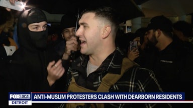 Jake Lang speaks as people surrouond him, including one wearing a face mask.