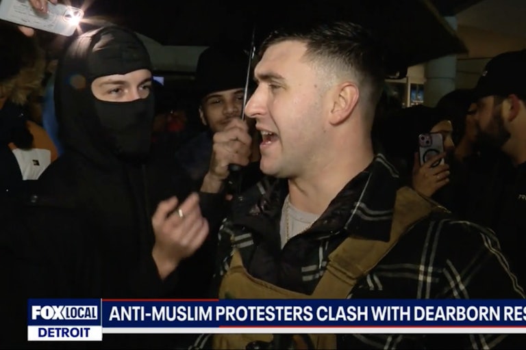 Jake Lang speaks as people surrouond him, including one wearing a face mask.