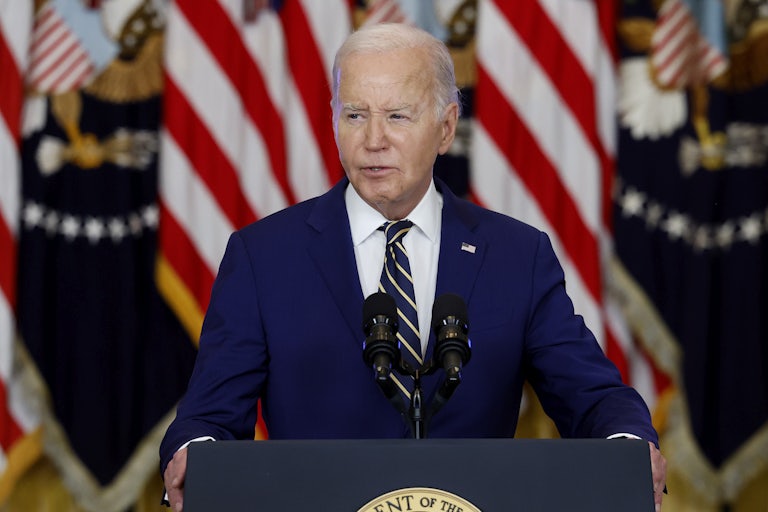 Joe Biden speaking at the presidential podium. U.S. flags are behind him.