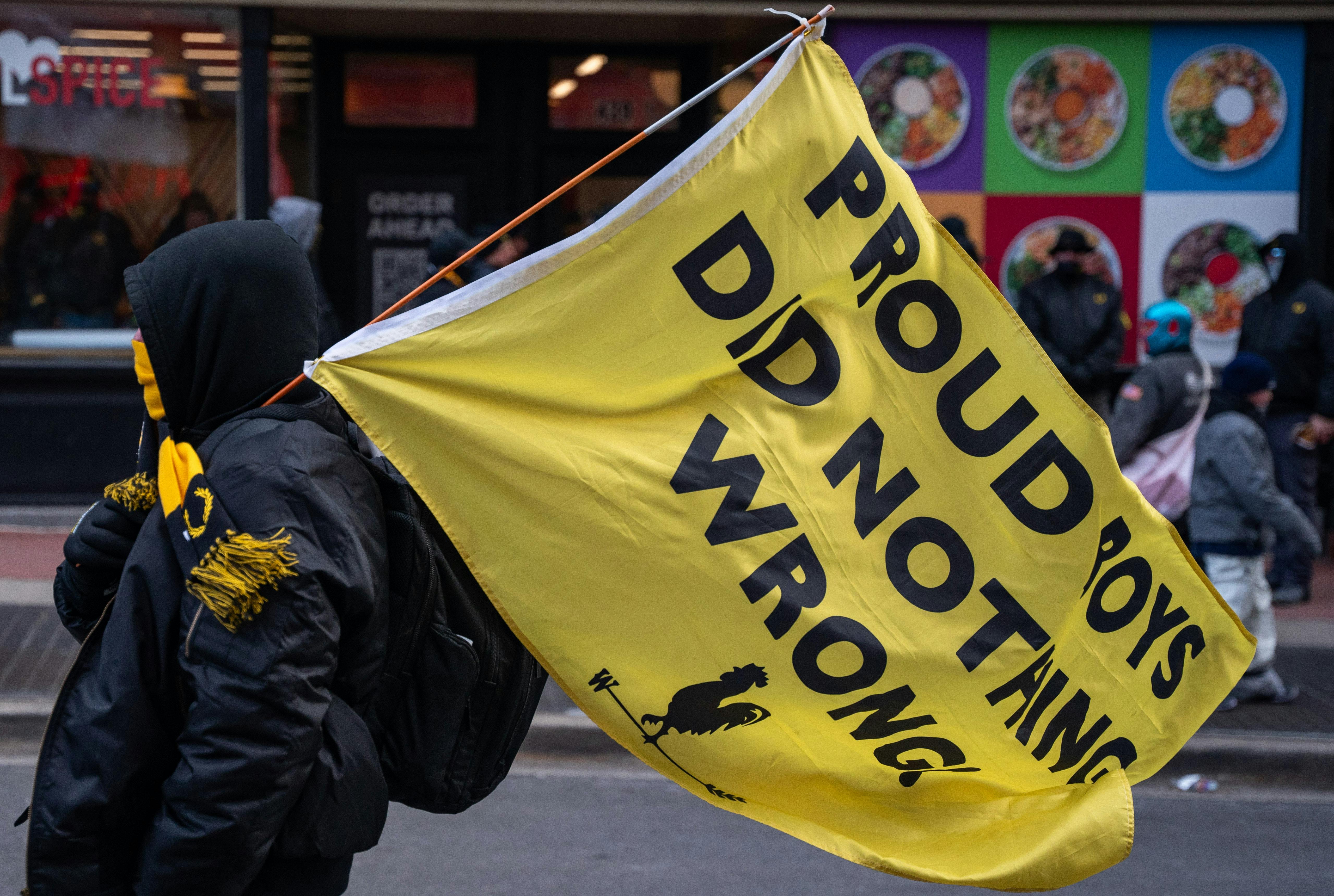 A member of the Proud Boys carries a flag reading "Proud Boys Did Nothing Wrong" 