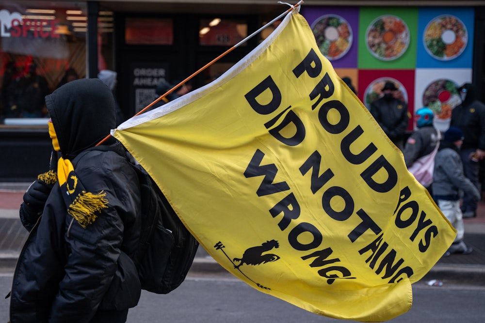 A member of the Proud Boys carries a flag reading "Proud Boys Did Nothing Wrong"