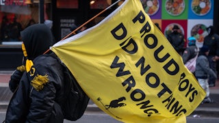 A member of the Proud Boys carries a flag reading "Proud Boys Did Nothing Wrong"