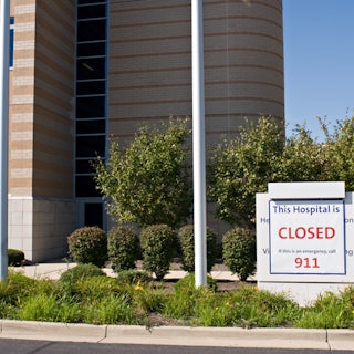 A sign in front of a hospital that reads THIS HOSPITAL IS CLOSED IF THIS IS AN EMERGENCY CALL 911