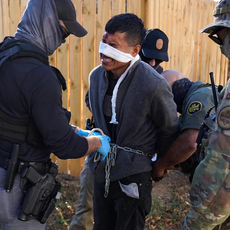 Innocent Americans are shown fleeing in the reflection of the gas mask of one of the administration's soldiers