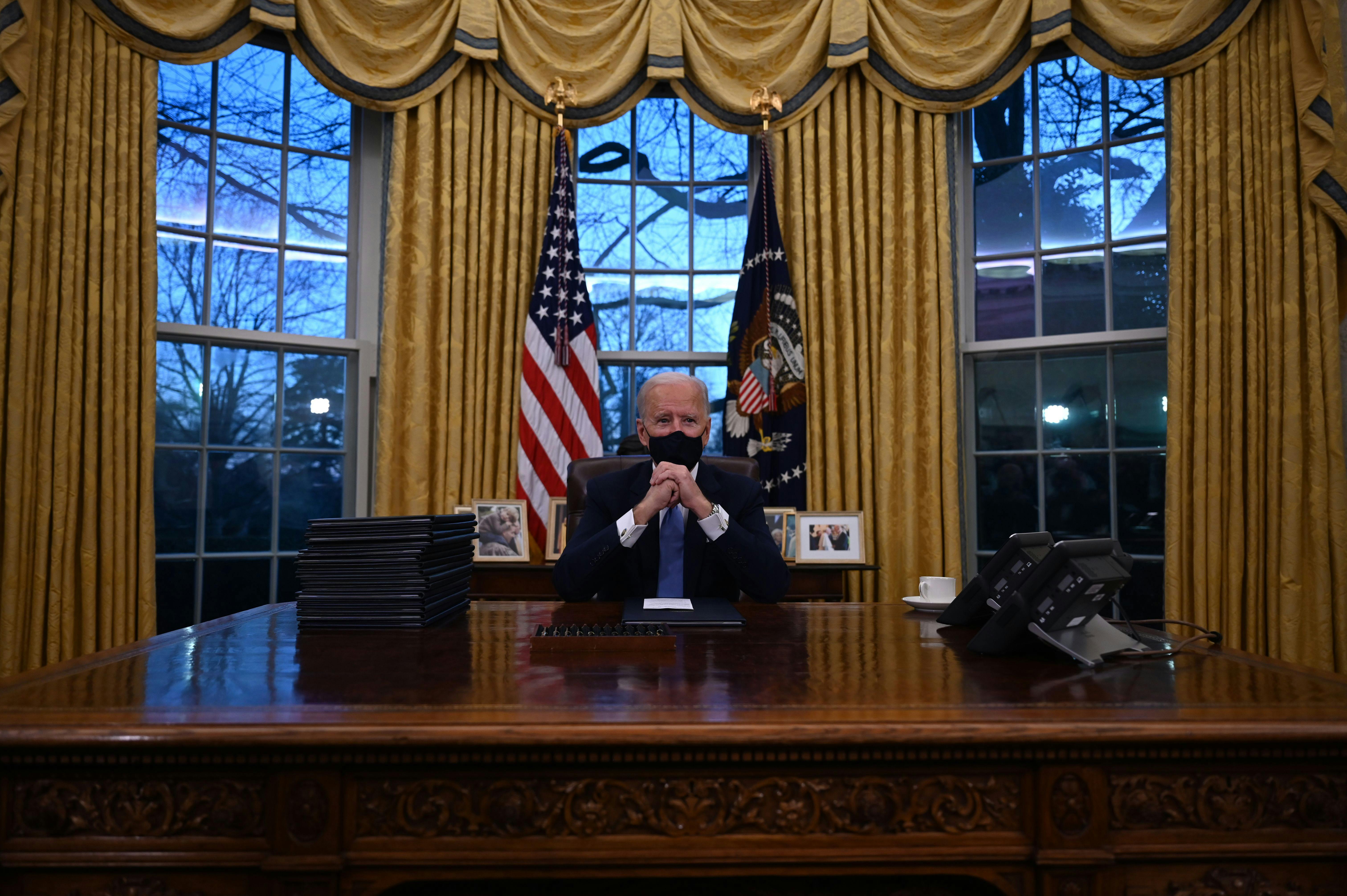 President Joe Biden sits behind his desk in the Oval Office.