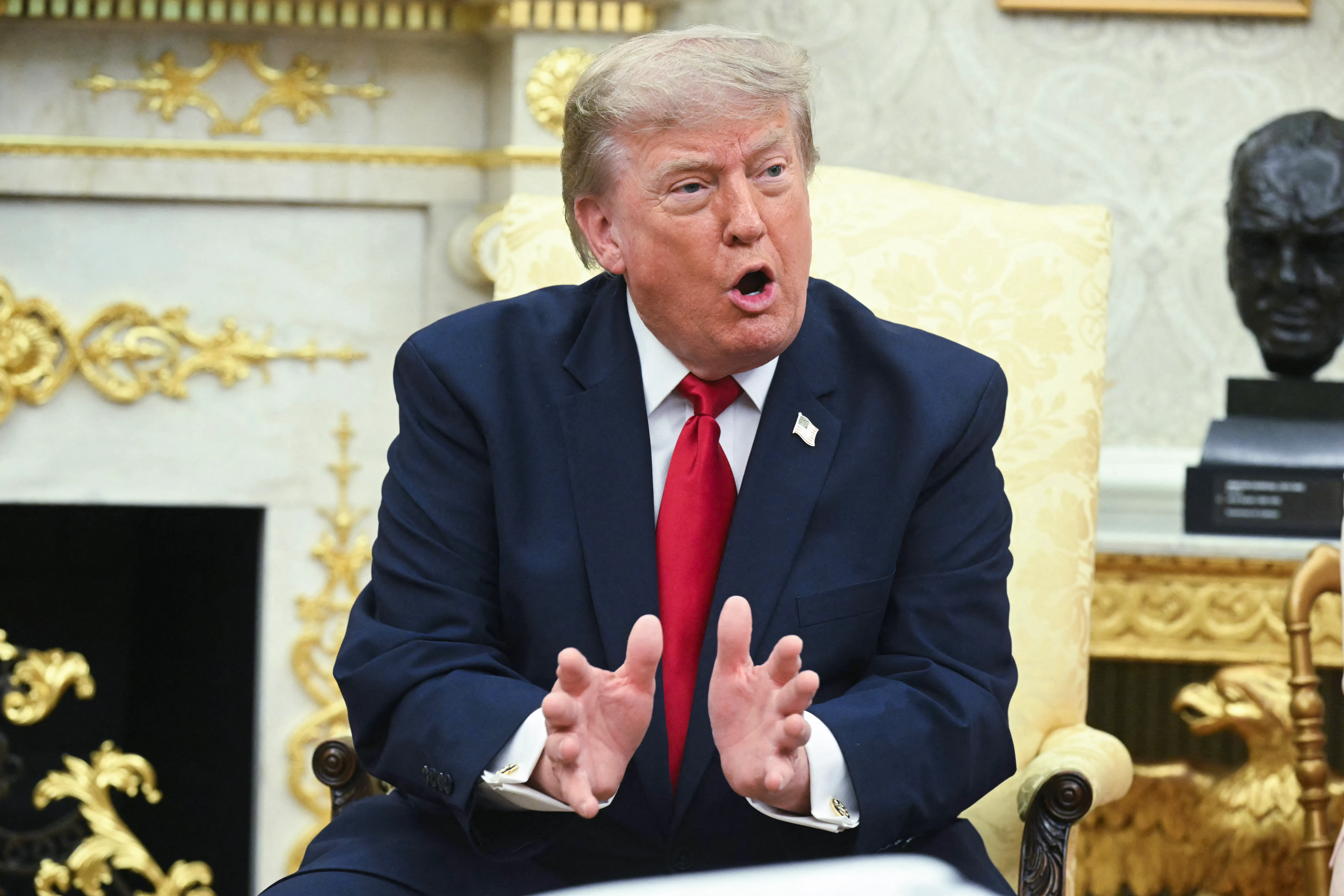 Donald Trump gestures and speaks while sitting in the Oval Office