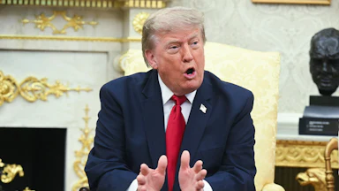 Donald Trump gestures and speaks while sitting in the Oval Office