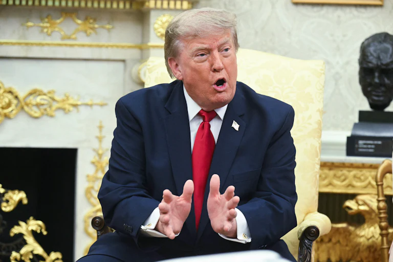 Donald Trump gestures and speaks while sitting in the Oval Office