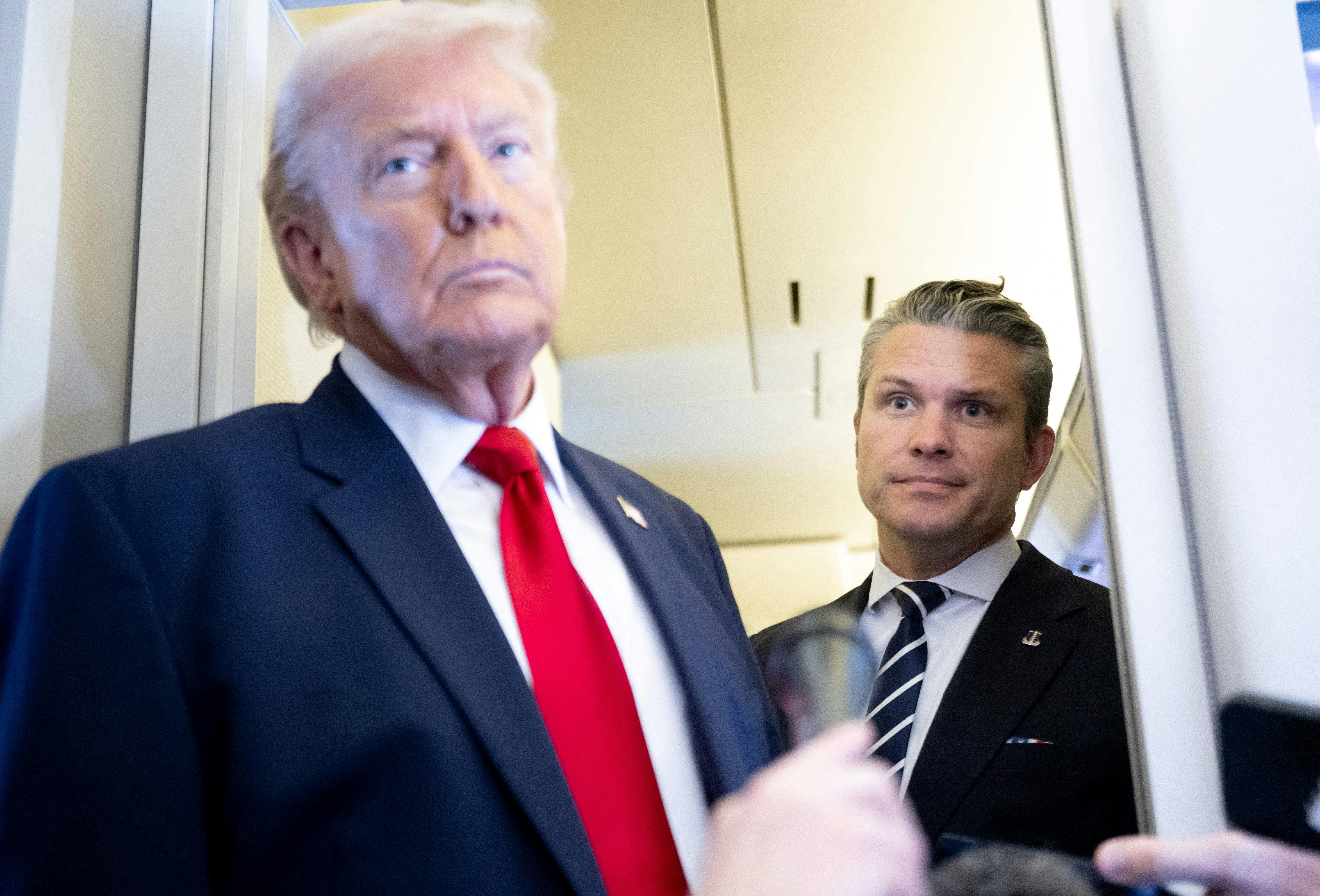 Donald Trump speaks with the media as Defense Secretary Pete Hegseth looks on aboard Air Force One