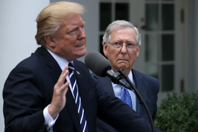 Mitch McConnell stands behind Donald Trump, who speaks at a lecturn