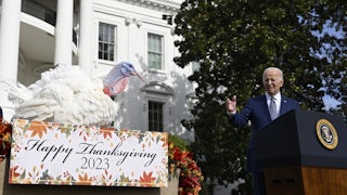President Biden stands at a podium pointing to a turkey.
