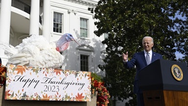 President Biden stands at a podium pointing to a turkey.