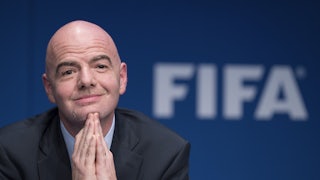 FIFA leader Gianni Infantino clasps his hands together and smiles.