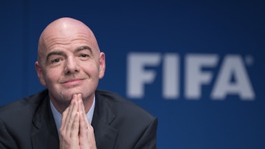 FIFA leader Gianni Infantino clasps his hands together and smiles.