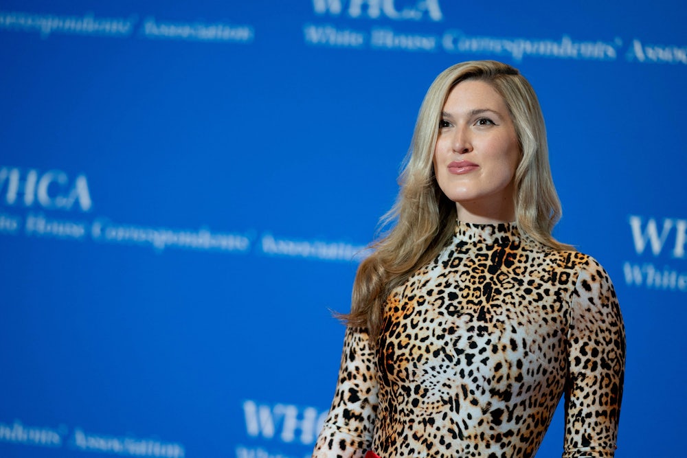 Olivia Nuzzi is shown from the waist up in an animal-print garment in front of a blue background.