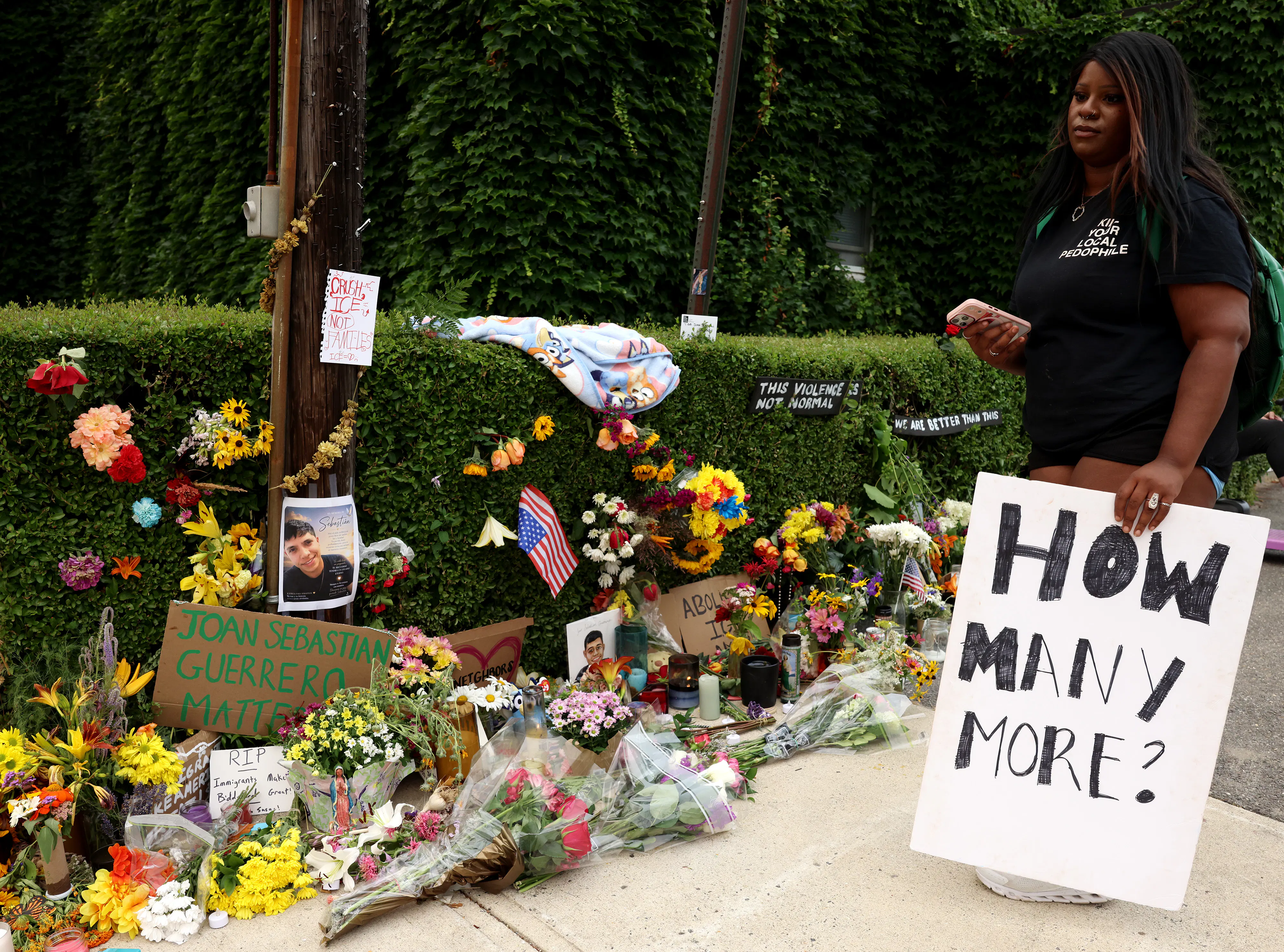 A woman holding a sign that reads "How many more?" visited a memorial for Joan Sebastián Durán Guerrero, who was killed by ICE agents in Biddeford, Maine, on July 13.
