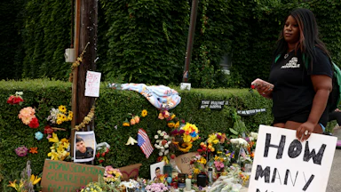 A woman holding a sign that reads "How many more?" visited a memorial for Joan Sebastián Durán Guerrero, who was killed by ICE agents in Biddeford, Maine, on July 13.