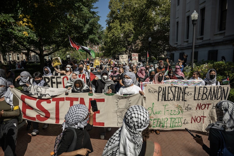 Protesting students wearing keffiyehs and face masks hold signs dedicated to Palestine and Lebanon