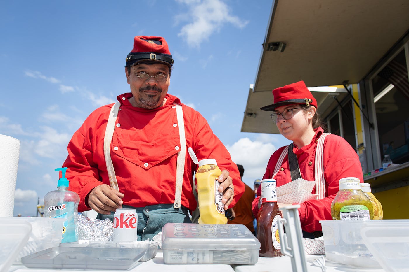 Reenactors in Civil War clothing take a meal break at the Lions Club food truck with soda, mustard and hand sanitizer. 