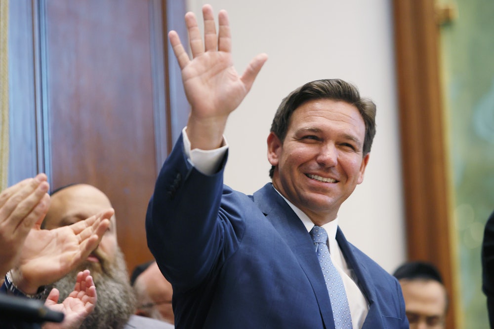 A smiling Ron DeSantis waves to a crowd.